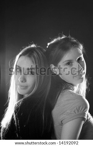 Black and white portrait of 2 sisters standing back to back