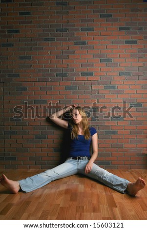 woman sitting on floor near brick wall looking hopeless