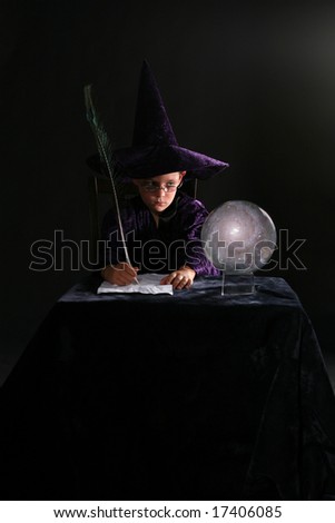 wizard boy looking into crystal ball and writing with a feather pen