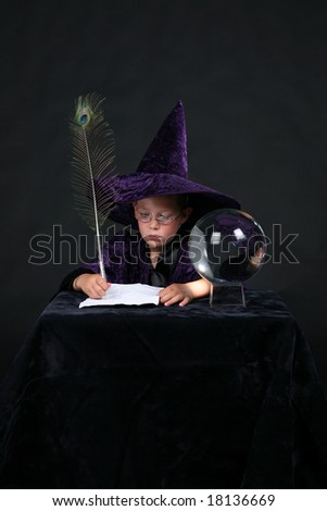 wizard child next to crystal ball writing a spell with a peacock feather pen