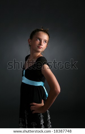 pretty girl in black dress with blue ribbon standing with hand on her hip