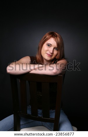 pretty teenage girl with red hair with arms crossed on the back of a chair