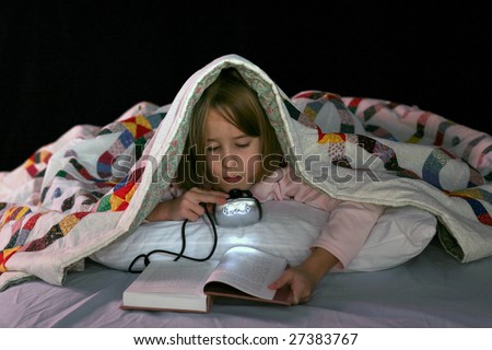cute girl reading in bed with a book light