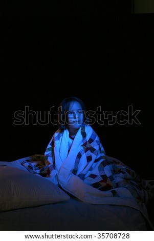 girl in the dark on a bed wrapped in quilt