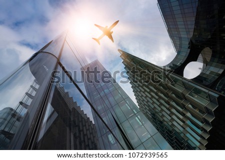 plane flying over highrise office buildings in the sun, financial district London, Great Britain