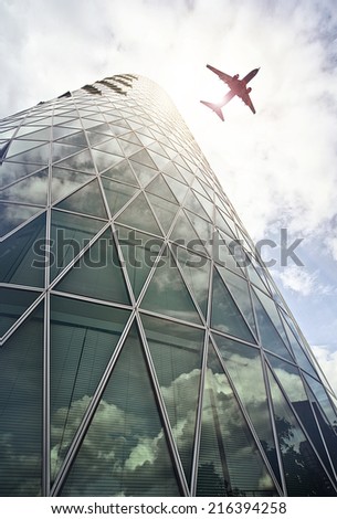 plane flying over a modern glass and steel office tower in the Westhafen district of Frankfurt am Main, Germany
