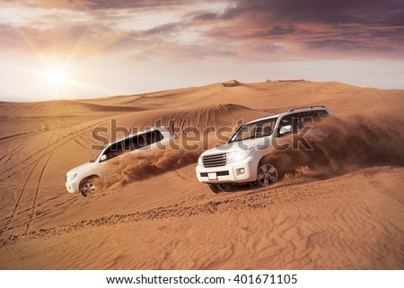 two 4x4 vehicles bashing side to side through the desert dunes in the evening sun