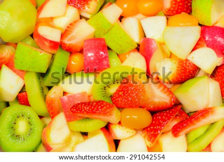 Motion blur de focused top view of fruit salad with strawberries, apple, kiwi for background, texture
