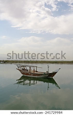 A small traditional fishing boat moored in the still waters of a creek in the United Arab Emirates.