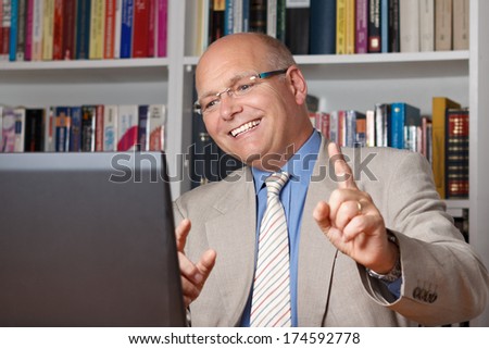 Happy old man celebrating in front of his computer