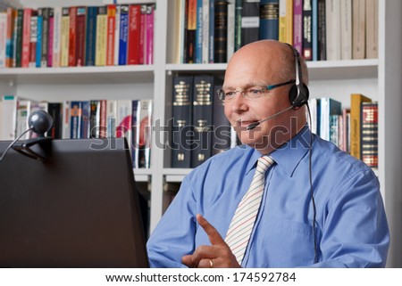 Friendly tutor talking with a student via headphones and internet