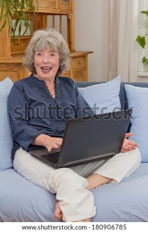 Senior woman on a couch cheering in front of her notebook