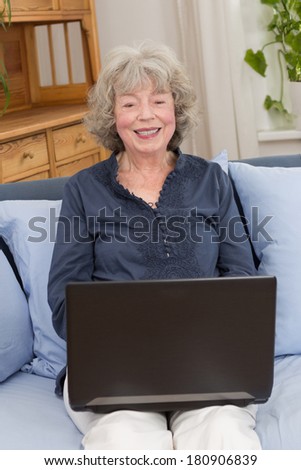 Smiling elderly woman with laptop on her lap