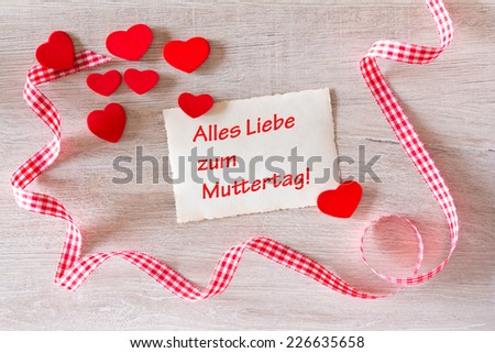 old yellowed card on whitewashed wood with many red hearts and red-white checkered ribbon in loops, text, Lots of love for mothers day