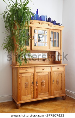 Old pine cupboard with glass and wooden doors, drawers, on oak herringbone parquet flooring