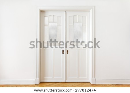 White wall with an old double sliding door with textured glass in an historic building, copy space