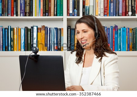 Smiling businesswoman in front of her computer in her office having a video call with her family at home, voip