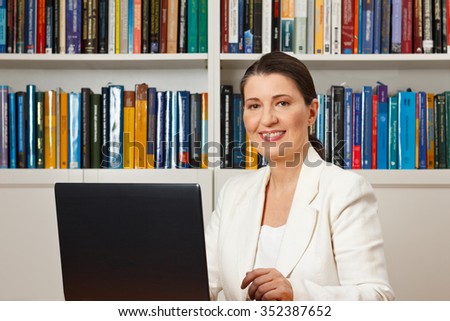 Friendly smiling woman in front of a computer in a library, consultant, counselor, adviser, customer service, online helpdesk