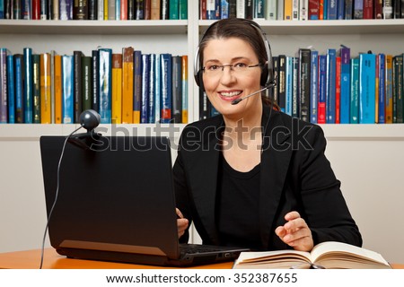 Smiling woman with headphone, computer and webcam in her office, consultant, adviser, teacher, online learning, business