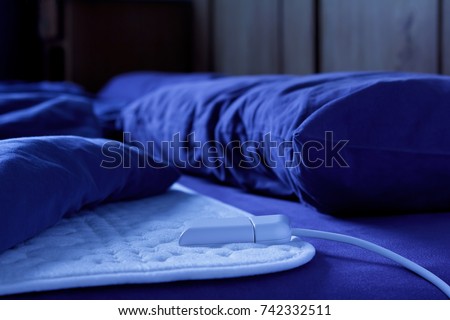 Electric heating blanket on a bed at night, thermotherapy for fibromyalgia syndrome and other rheumatic diseases