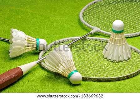 Rackets and shuttlecocks for badminton on a green background.