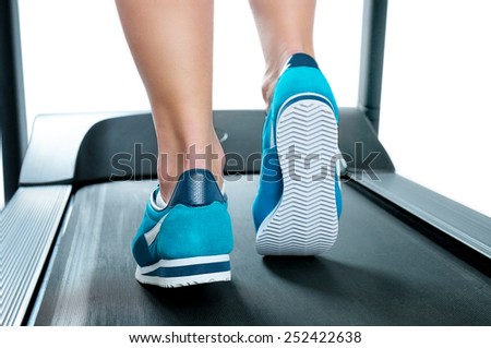 Female legs in turquoise sneakers on a treadmill. Back view.