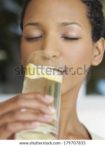 Beautiful black woman drinking water with lemon