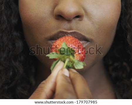 Beautiful black woman eating strawberry fruit