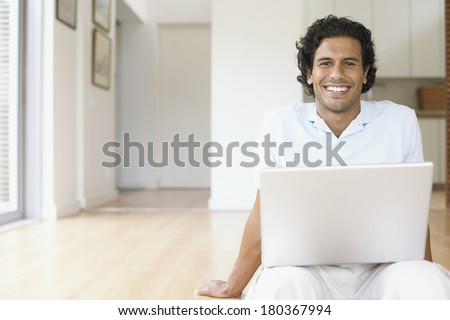 Young man using laptop computer, searching on internet at home