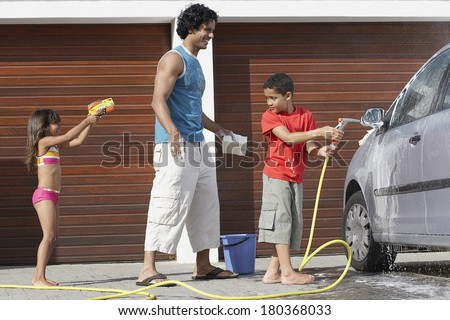 Father and children washing car at home