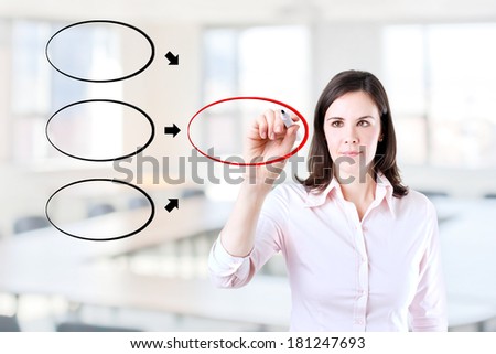 Young business woman drawing diagram on whiteboard. Office background.