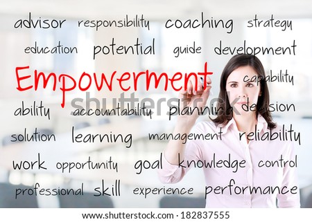 Young business woman writing empowerment concept. Office background.