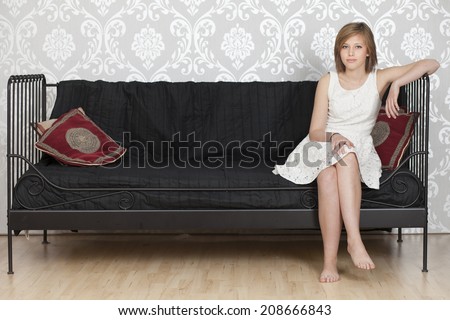 Girl in summer dress sitting on a sofa