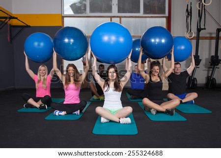 Medicine ball fitness training - sports team sitting on yoga mat