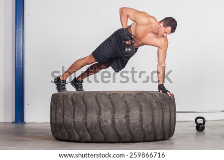 man doing kettlebell training on a tire crossfit