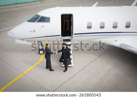 executive manager leaving corporate jet handshake with pilot