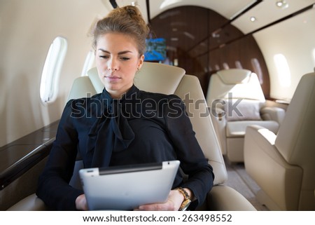 woman in corporate jet looking at tablet computer
