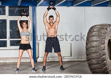 man and woman swing kettle bell