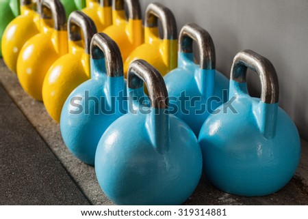 colorful kettlebells in a row in a gym - focus on the front kettle bell