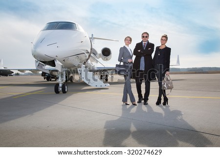 business team standing in front of private jet