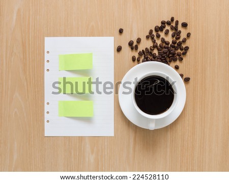 Paper stick and empty paper sheet with coffee cup and coffee beans on wooden background.