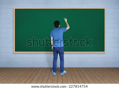 Young man writing something on blackboard in room.