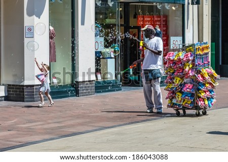 TUNBRIDGE WELLS, KENT/UK - JUNE 30 : Man generating lots of bubbles in the shopping centre at Royal Tunbridge Wells on June 30, 2009. Unidentified man and girl.