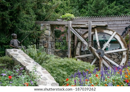 BRENTWOOD BAY, VANCOUVER ISLAND/CANADA - AUGUST 11 : Bronze statue of boy fishing next to an old water wheel at Butchart Gardens in Brentwwod Bay Vancouver Island on August 11, 2007