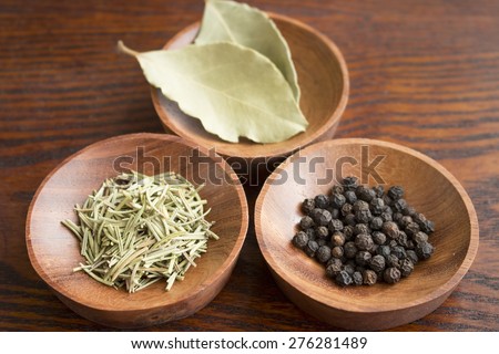 Dry herb served in wooden plate, rosemary, bay leaf, black pepper