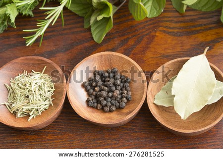 Dry herb served in wooden plate, rosemary, bay leaf, black pepper, flesh herb