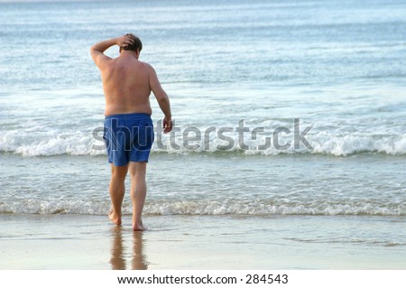 Photo of an obese man walking into the water.