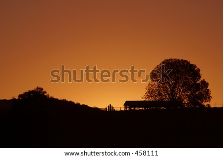 Photo of a sun setting behind a country shed.