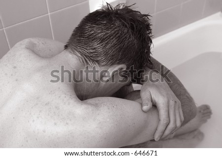 Photo of a man in the bath looking depressed.
