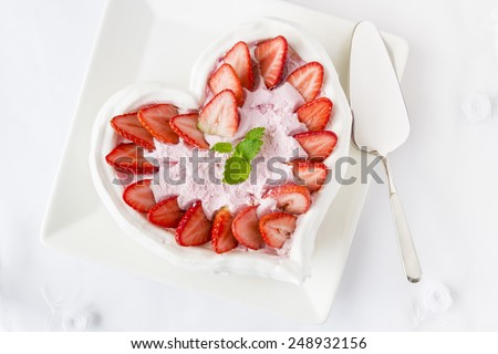 Meringue cake with strawberries, cream and raspberries and silver cake slicer.